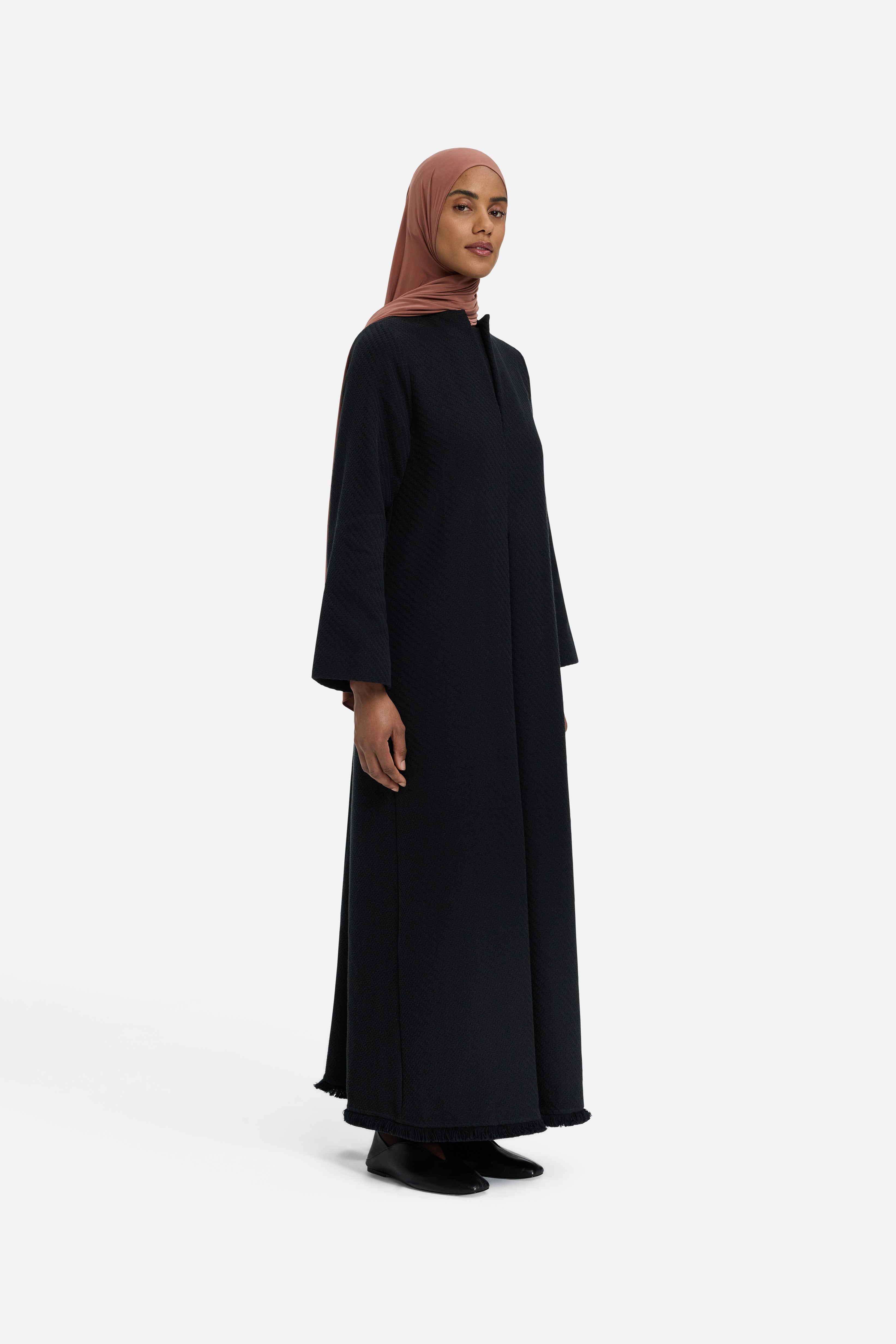 Side view model wearing black dress and pink headscarf