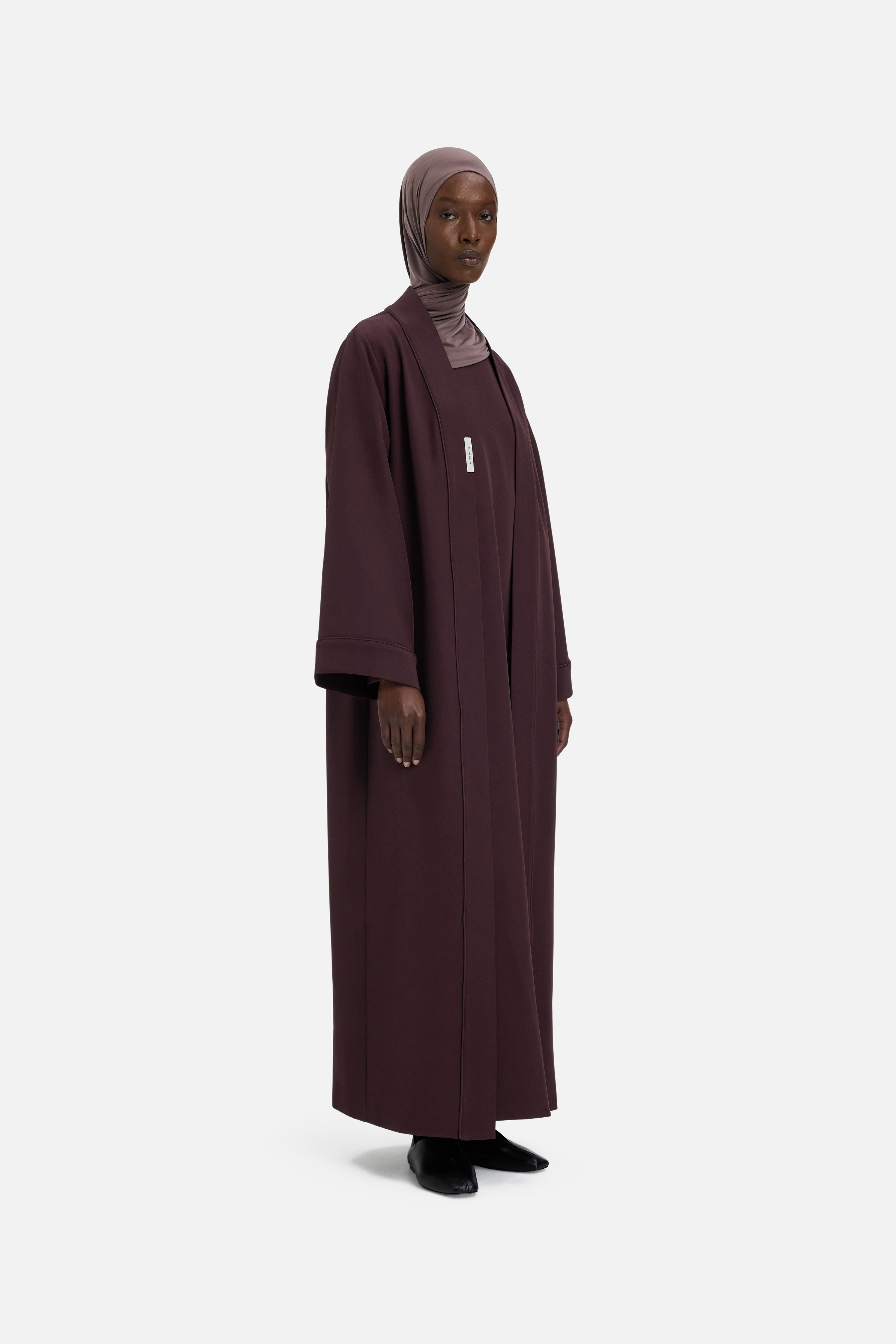 Model wearing purple abaya and headscarf, side view