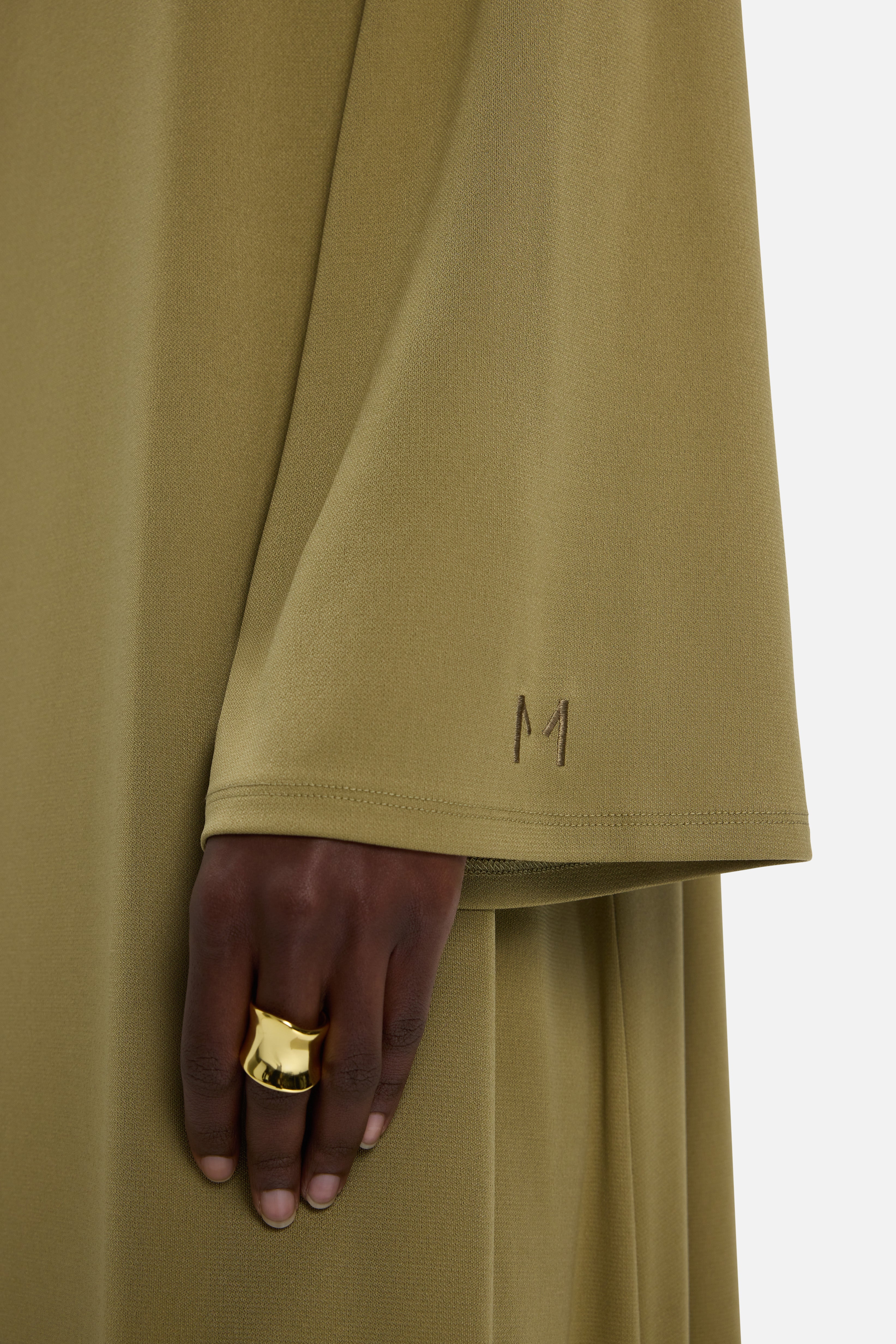 Sleeve detail MERRACHI logo on green dress