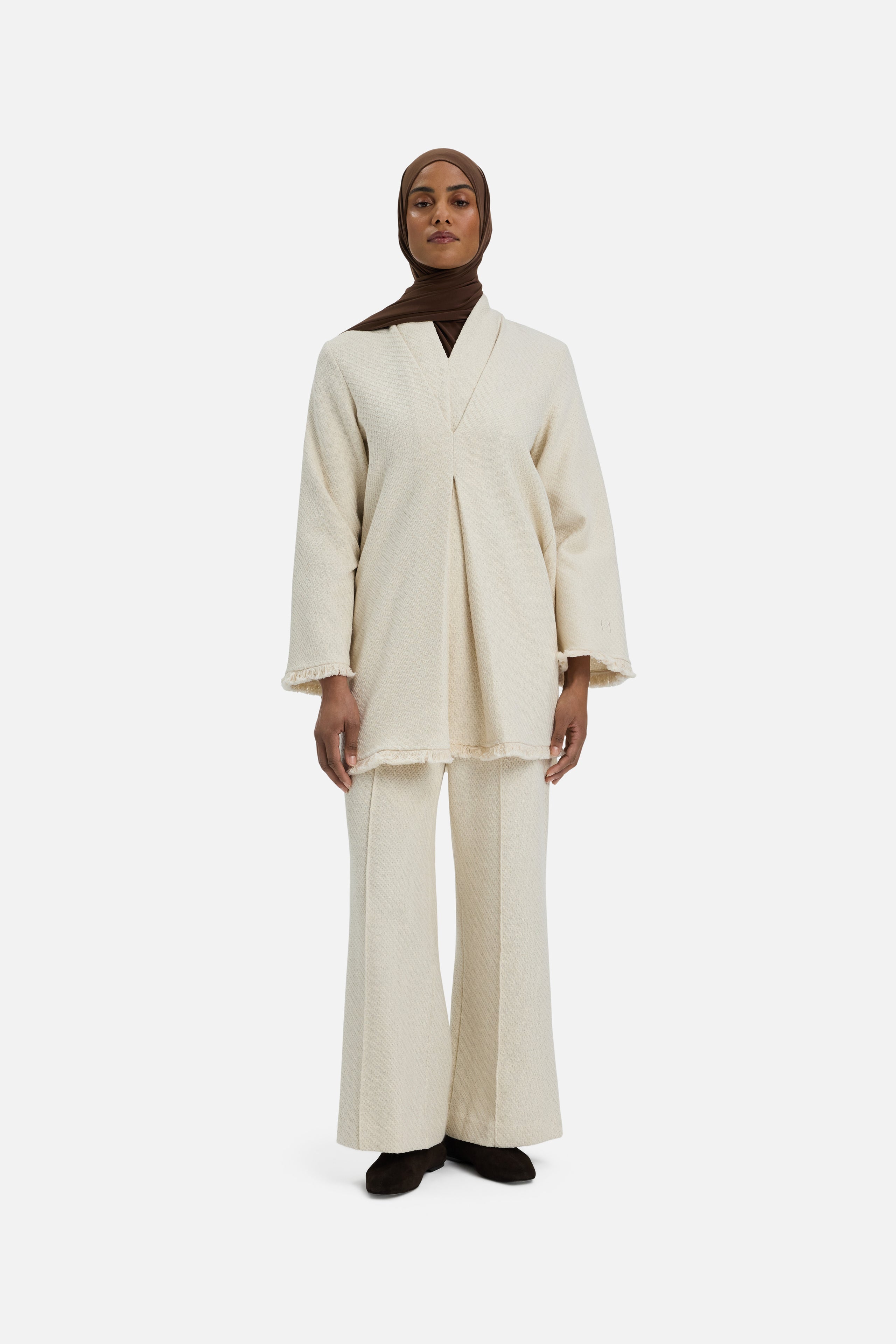 Front view model wearing white trousers and brown headscarf