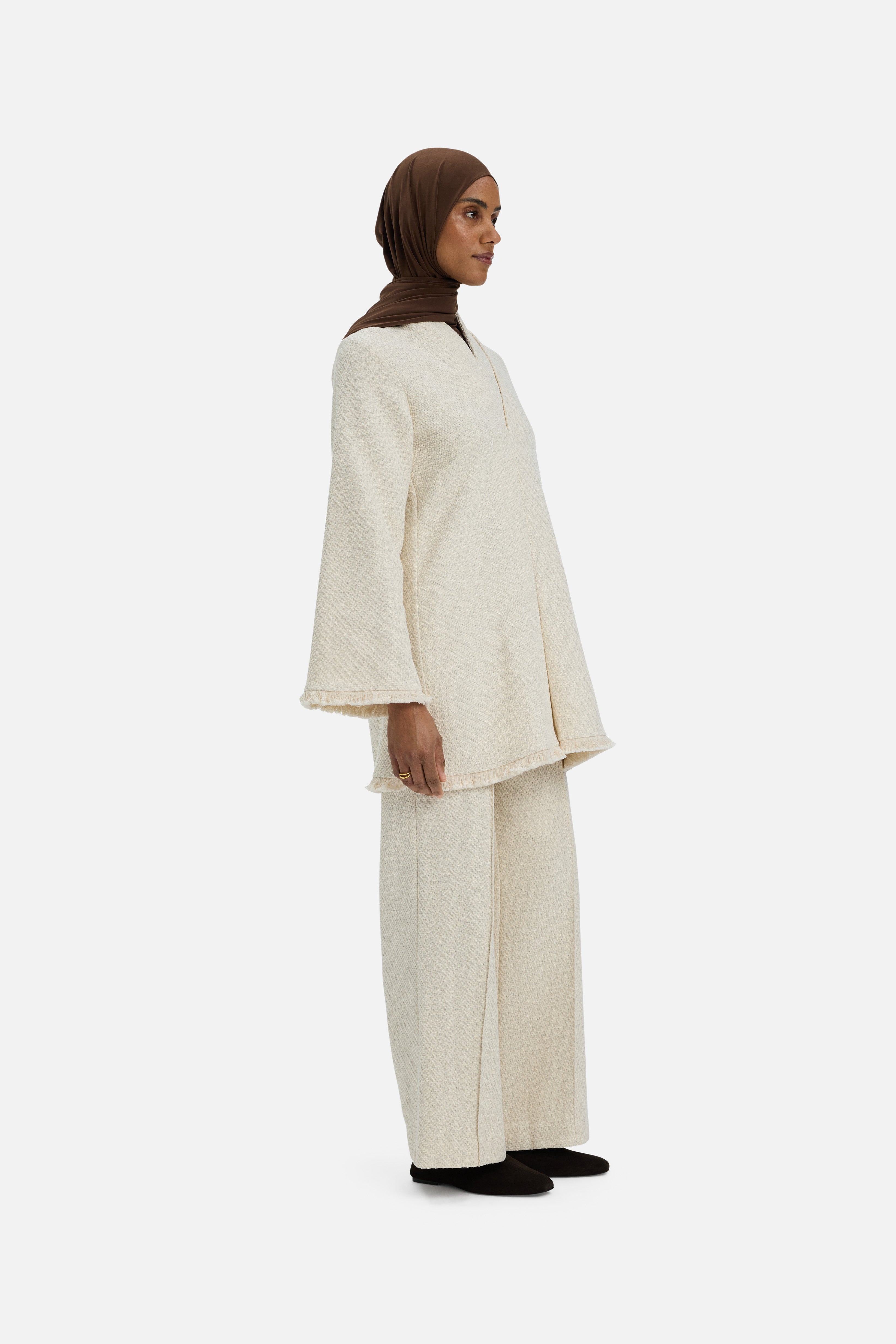 Side view model wearing white trousers and brown headscarf