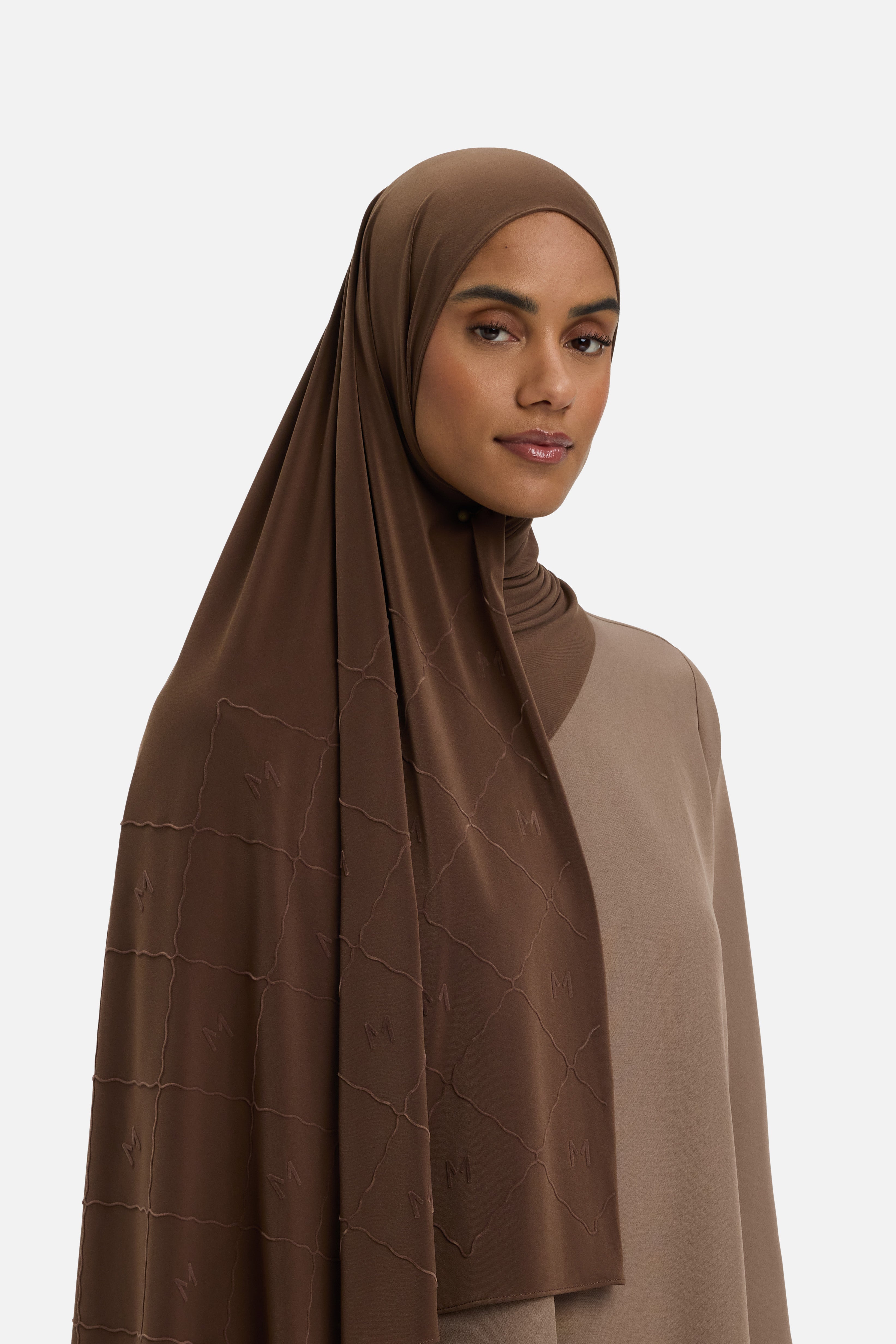 Model wearing dark brown headscarf MERRACHI logo and embroidery, side view