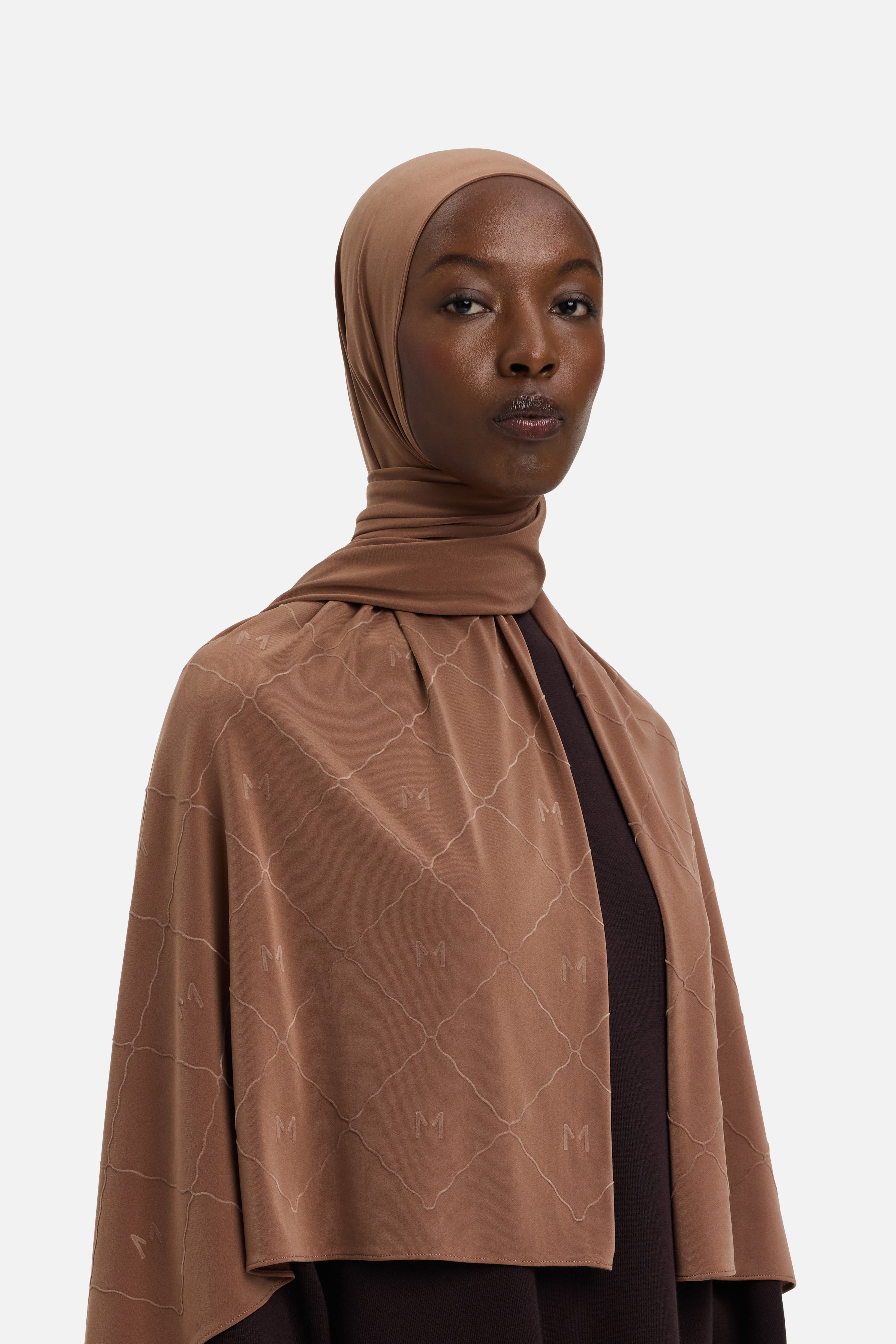 Model wearing brown headscarf MERRACHI logo and embroidery, side view
