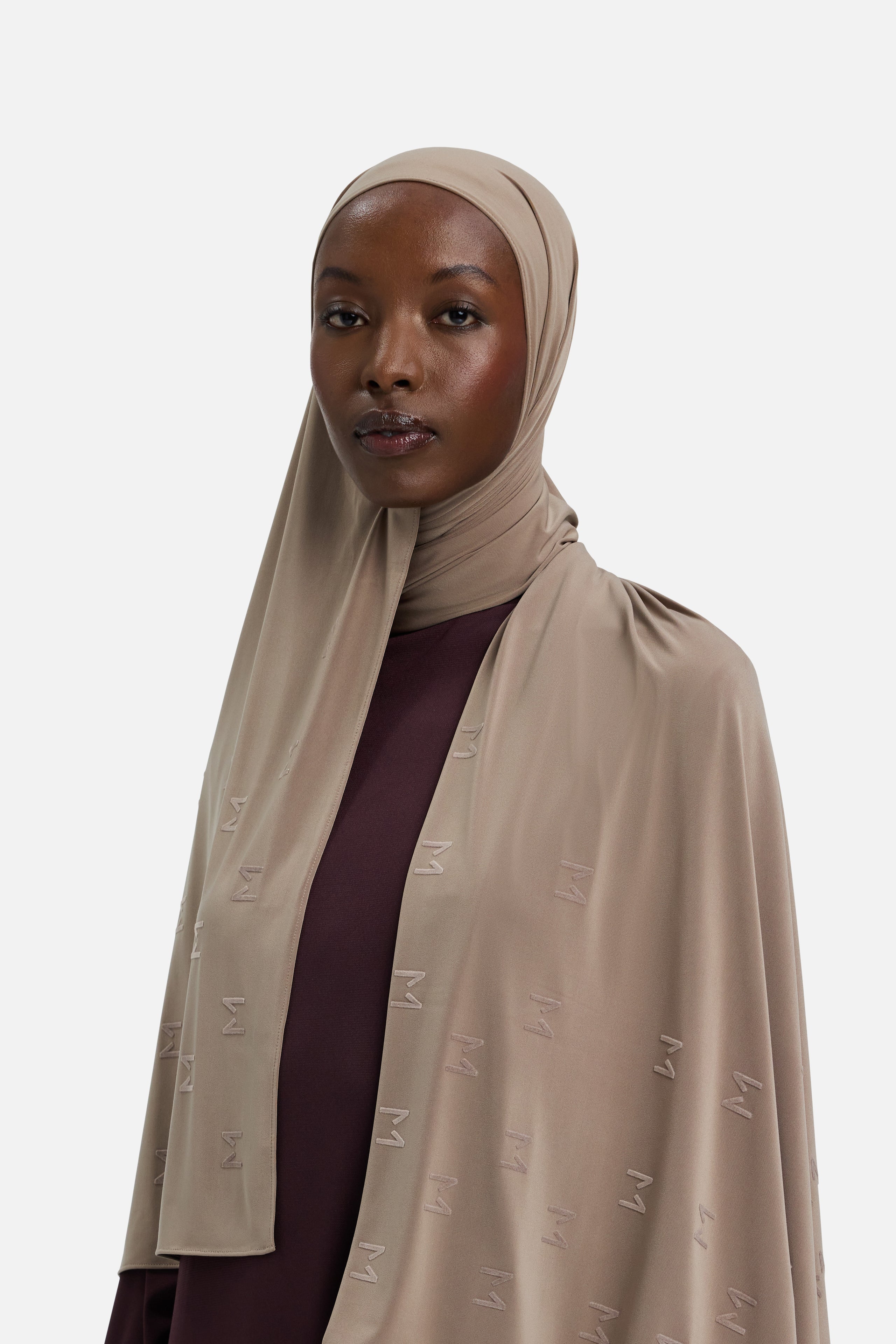 Model wearing taupe headscarf MERRACHI logo embroidery, front view